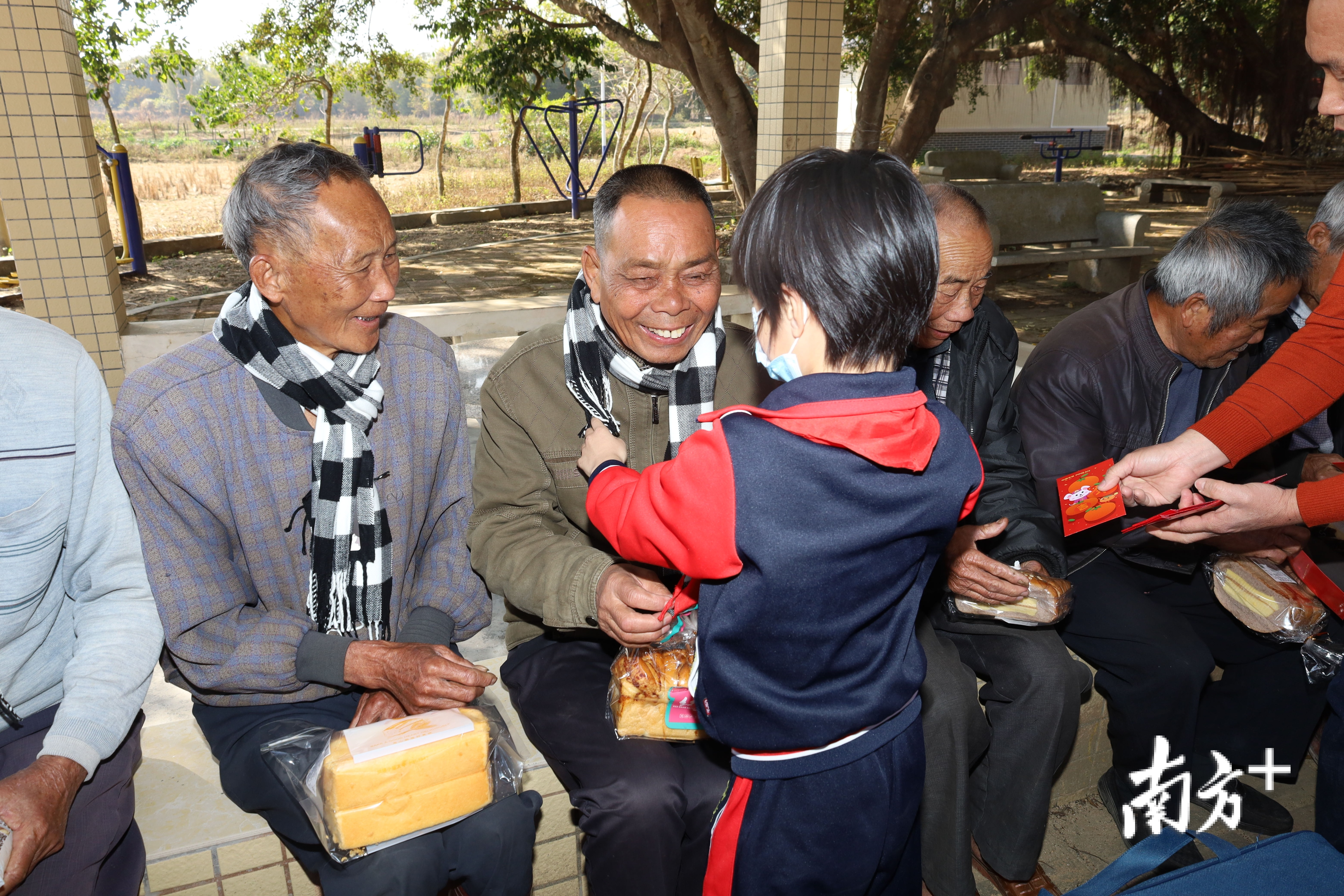 小志愿者为老人送上围巾。