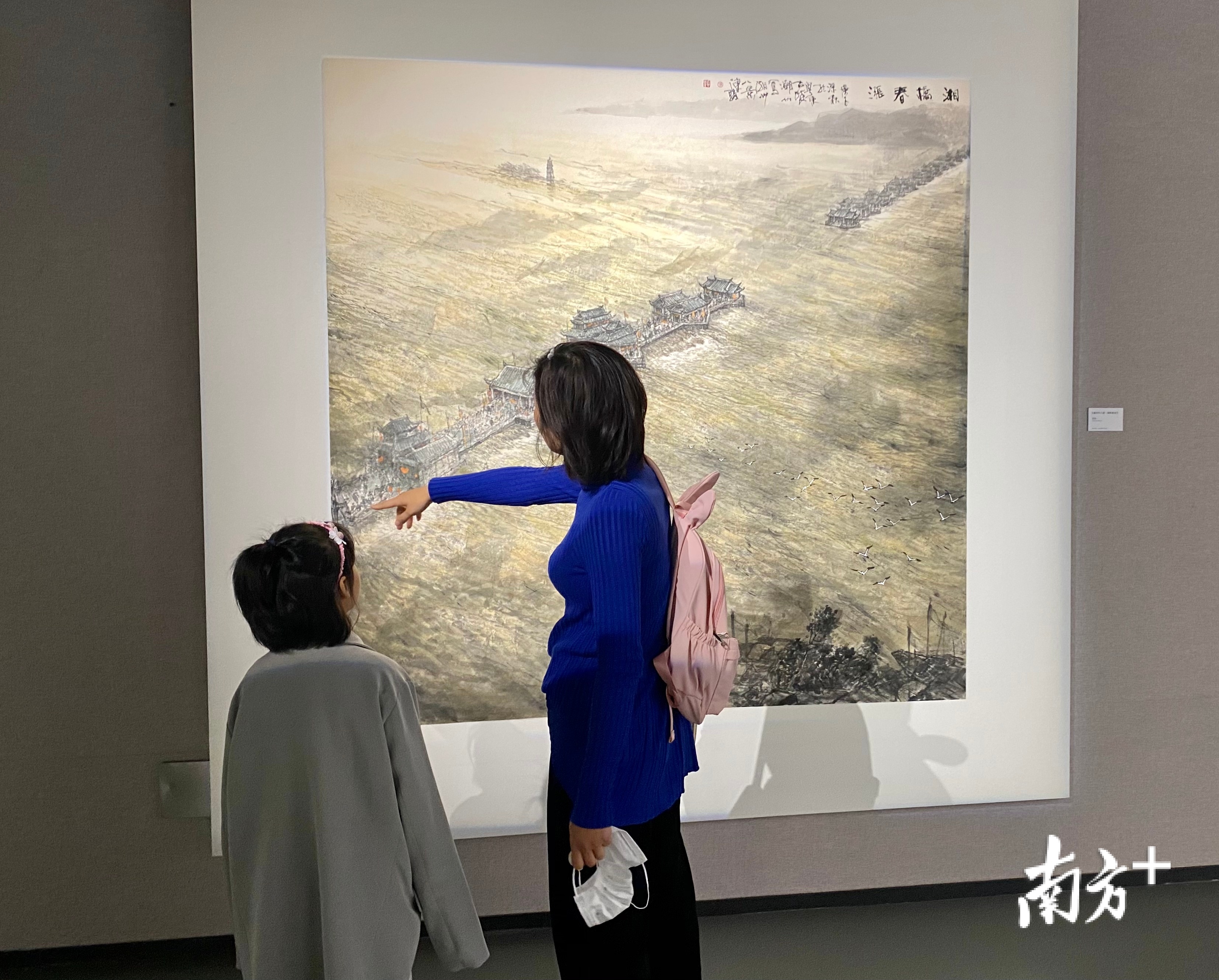 刘女士一边看画一边给女儿讲解。