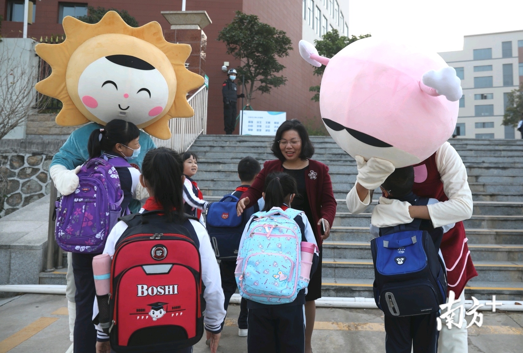 珠海市金湾区虹晖小学的学生走进校园,学校吉祥物“虹虹”、“晖晖”和校长李彩芳在门前迎接学生们的到来。