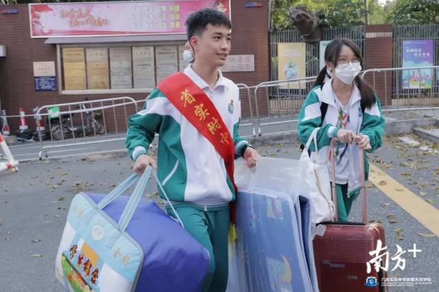 师生志愿者帮助分批返校的学生校搬运行李。