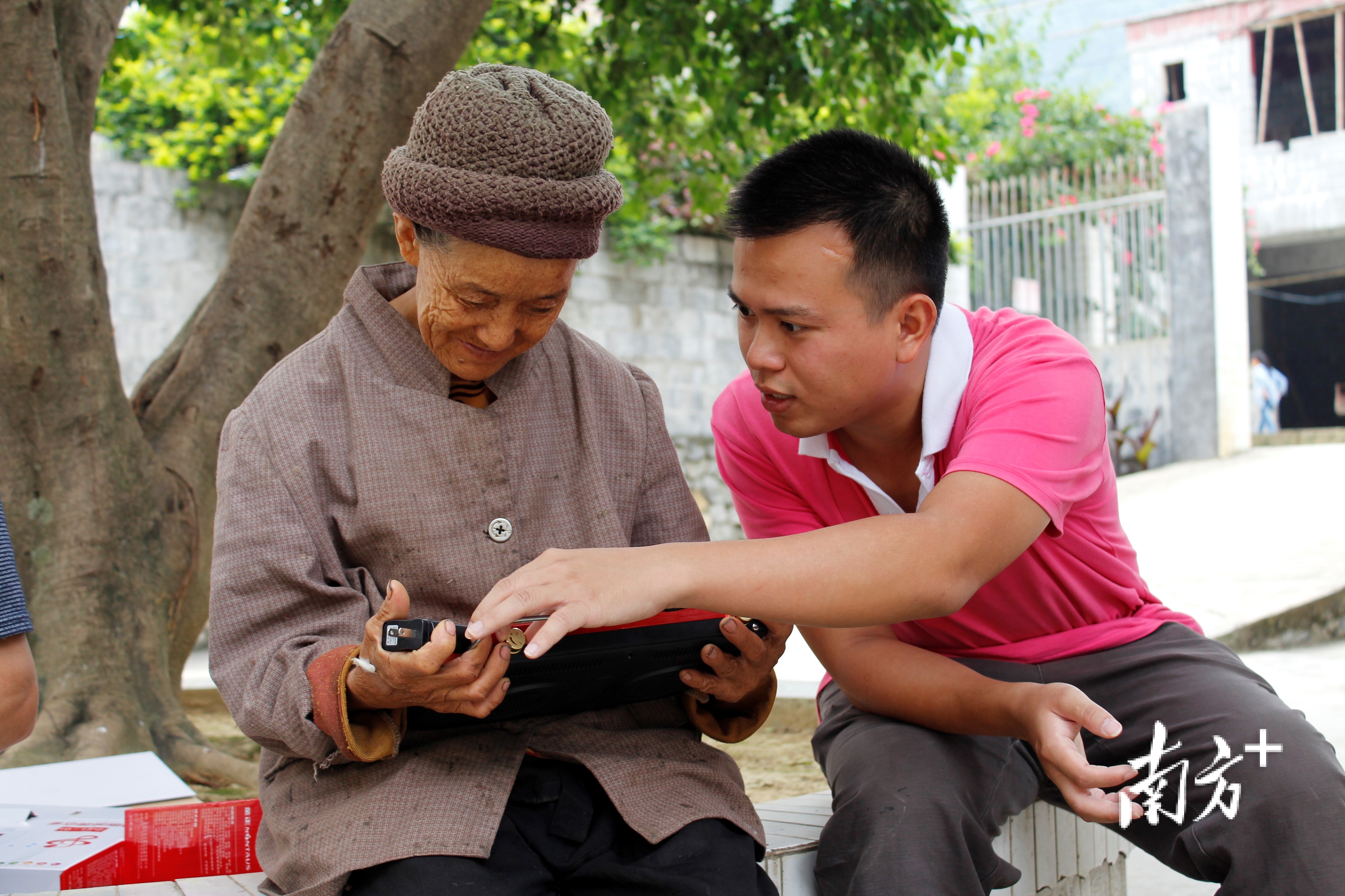 图说：志愿者吴道杰在教老人使用收音机。（右一）