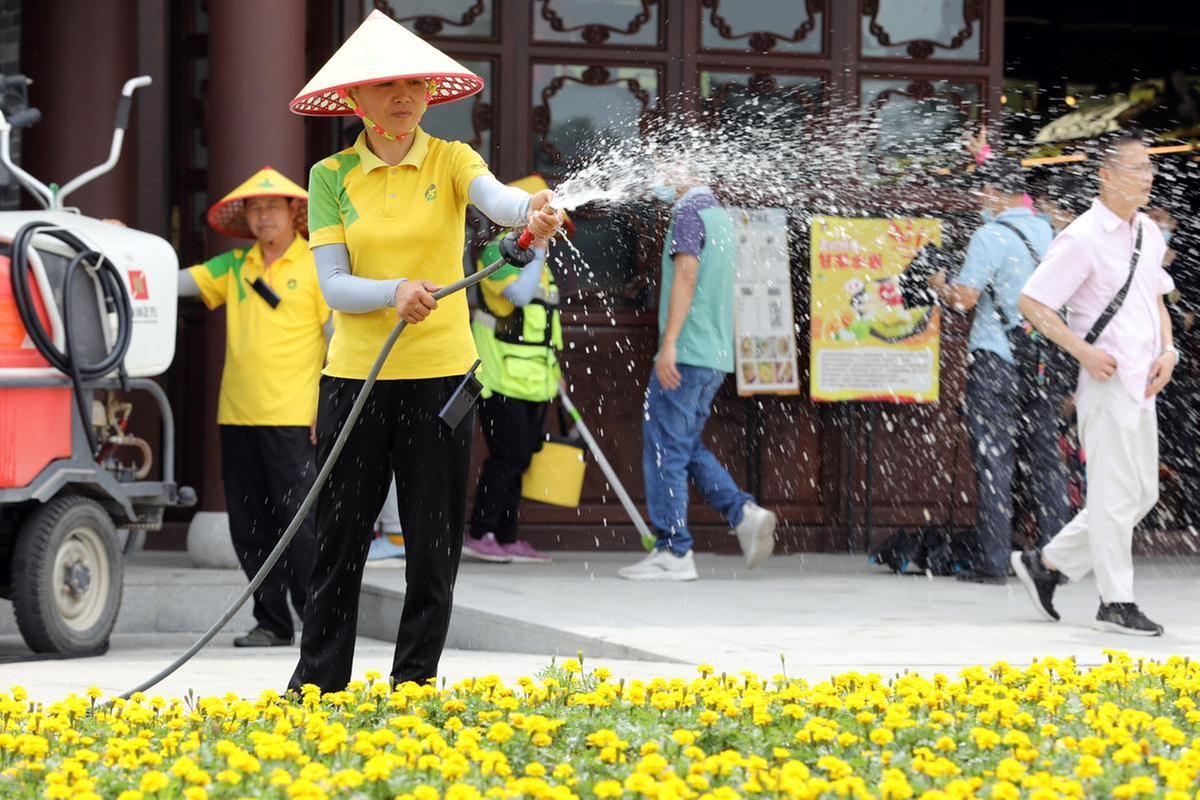 谭梅为公园花卉浇水,为游客提供美丽的环境。 谭梅为公园花卉浇水,为游客提供美丽的环境。