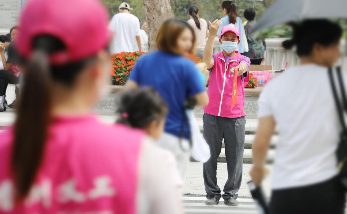 邱镇茂手持写有“绿色出行文明出行”字眼的旗帜疏导过往行人车辆。 邱镇茂手持写有“绿色出行文明出行”字眼的旗帜疏导过往行人车辆。