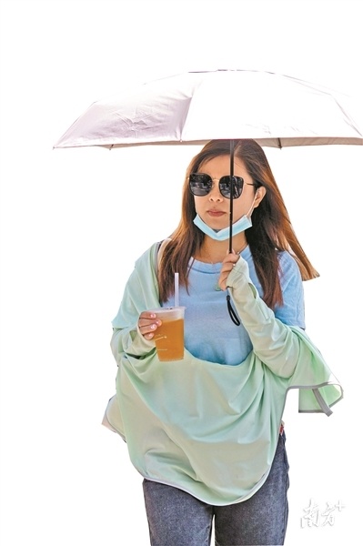 夏天来了,一位女士穿着防晒衣加撑伞防晒.苏俊杰 摄