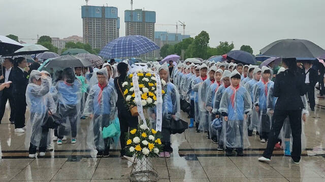 袁隆平故乡师生雨中缅怀，学生手捧白花鞠躬悼念