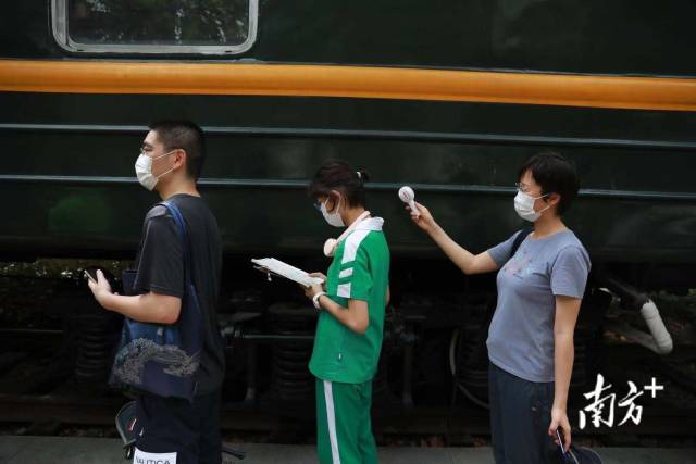 越秀区白云街现场，执信中学初二的潘同学和爸爸妈妈一起前来排队就测核酸，排队等候间隙她拿出一本历史书，妈妈拿着小风扇帮她吹风。“平时喜欢看书，就带着书来了，”她害羞地表示，九点钟过来排队，现场秩序挺好。【南方日报 南方+记者】冯艳丹  摄