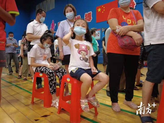 【海珠体育中心】提醒：分批次凭预约号采样检测，避免扎堆在海珠体育中心的核酸检测点，素社街道的居民在羽毛球馆内排队检测核酸，室内控制在100人左右，整体有序。为了提高效率，等候通道上摆放了一些凳子，提供给有需要的居民。同时，每隔几米就张