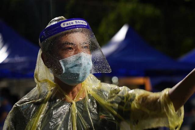 6月1日晚，荔湾区东沙街道核酸检测点，街道工作人员在雨中引导市民有序排队检测核酸。 