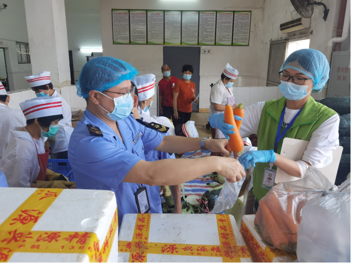 开平市开侨中学，检查人员和抽检人员对当天供应的蔬菜进行抽检。