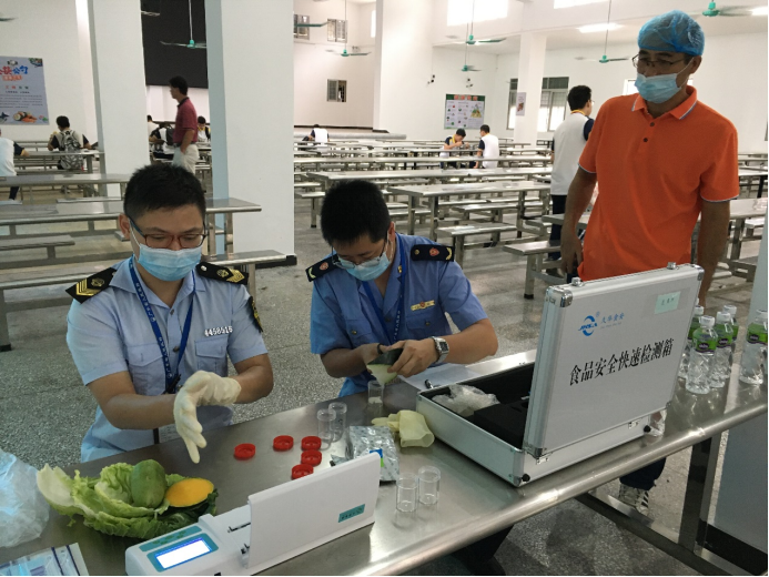 在恩城中学，执法人员对果蔬进行快检。