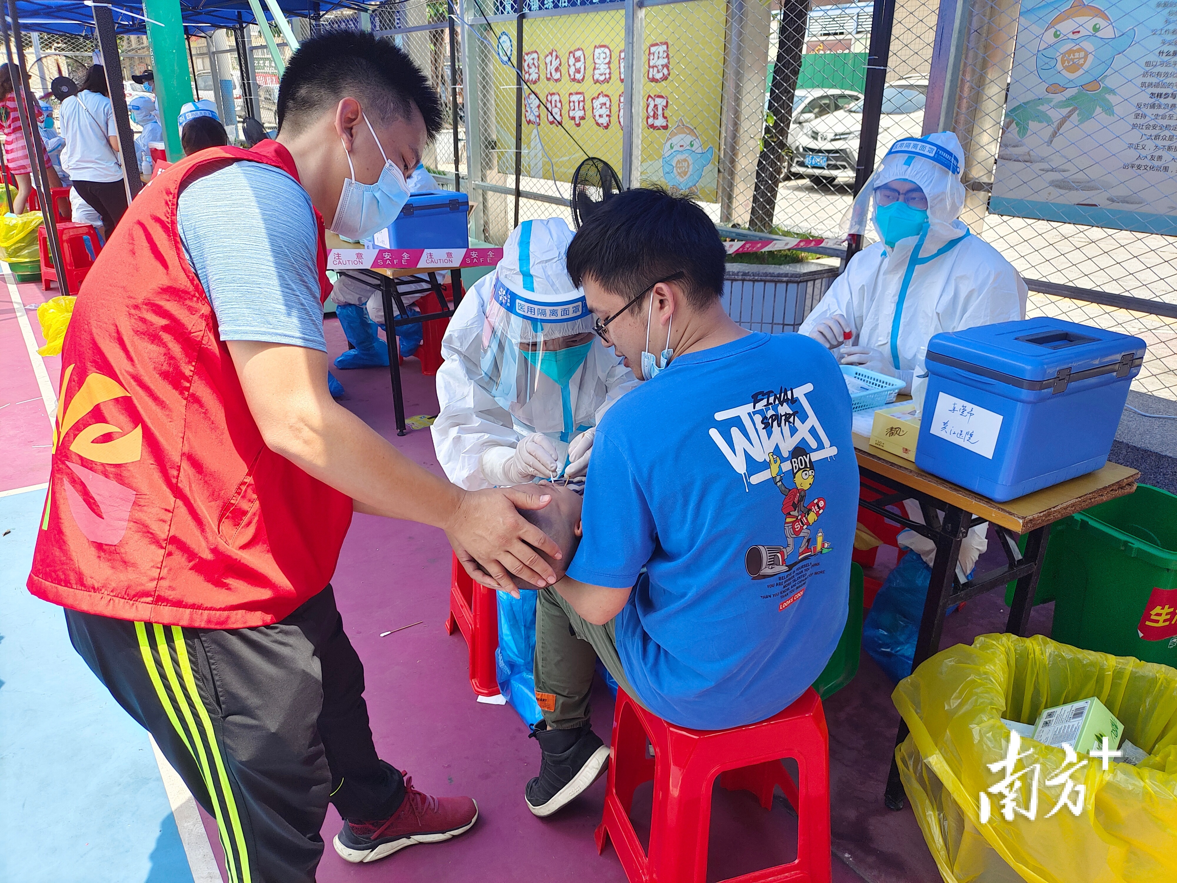 在志愿者的辅助下，医护人员为小孩进行核酸采样。黄政正 摄
