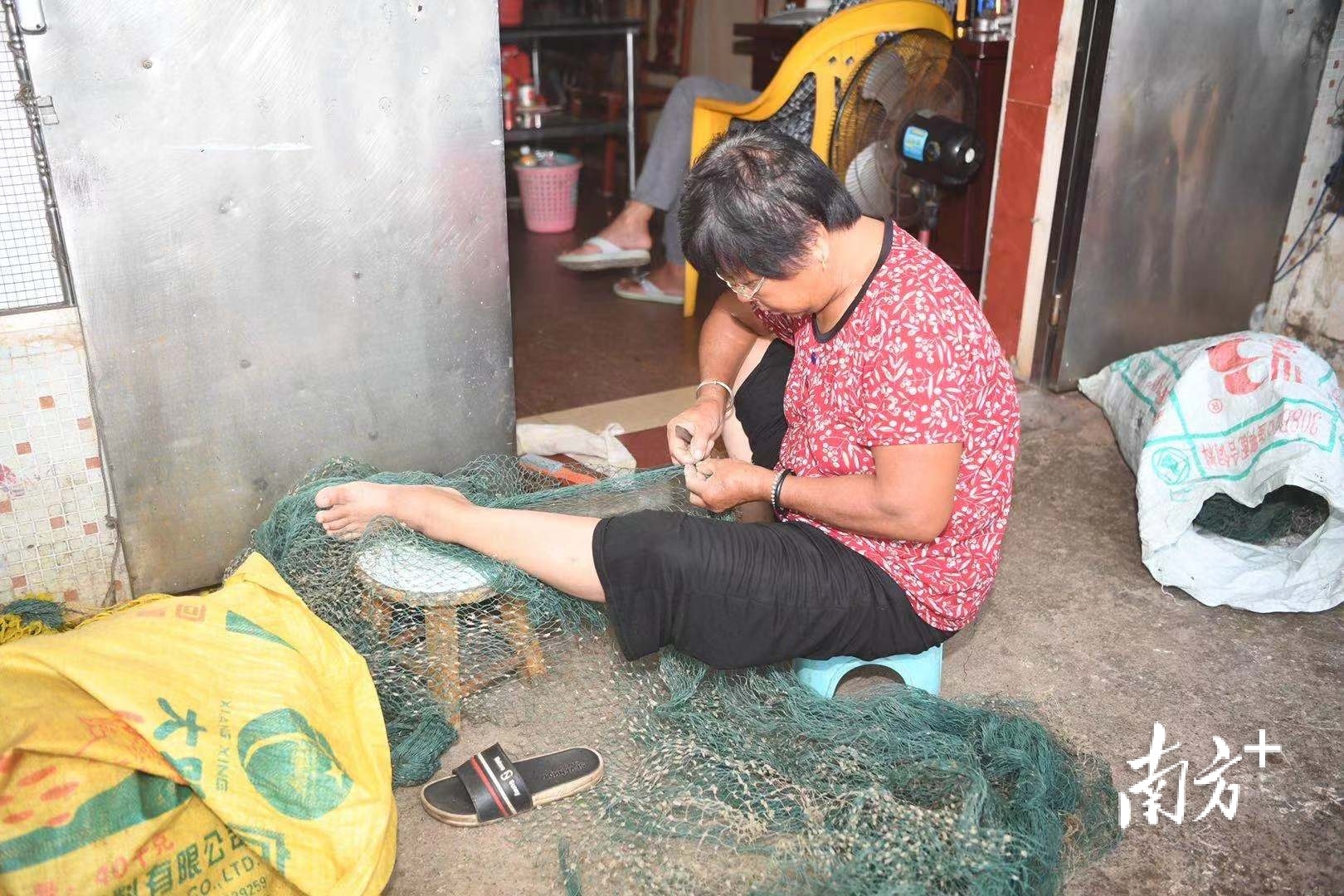 岸上渔民在家补网，在户外的不忘望一眼渔船情况。