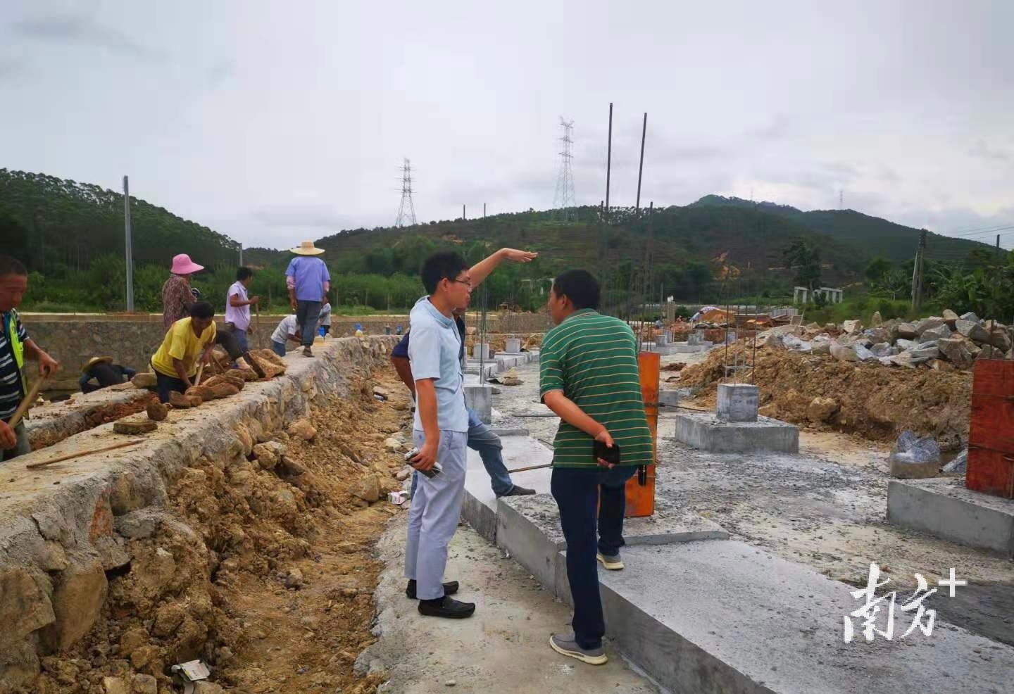 在高明坟典村，规划师黄如波与施工方探讨如何修建水坝。受访者供图