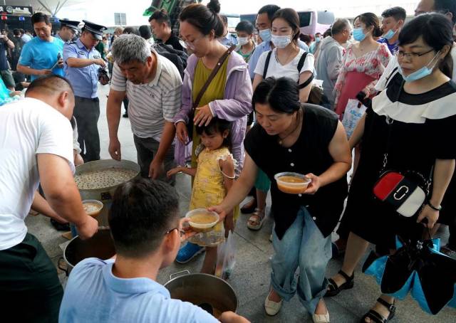 7月21日，工作人员在郑州东站进站口处为滞留旅客提供早餐。