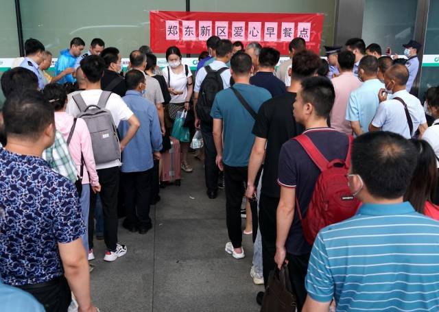 7月21日，滞留旅客在郑州东站进站口处排队领取早餐。
