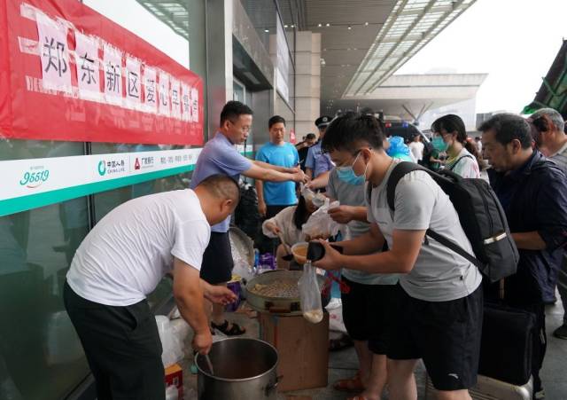 7月21日，工作人员在郑州东站进站口处为滞留旅客提供早餐。