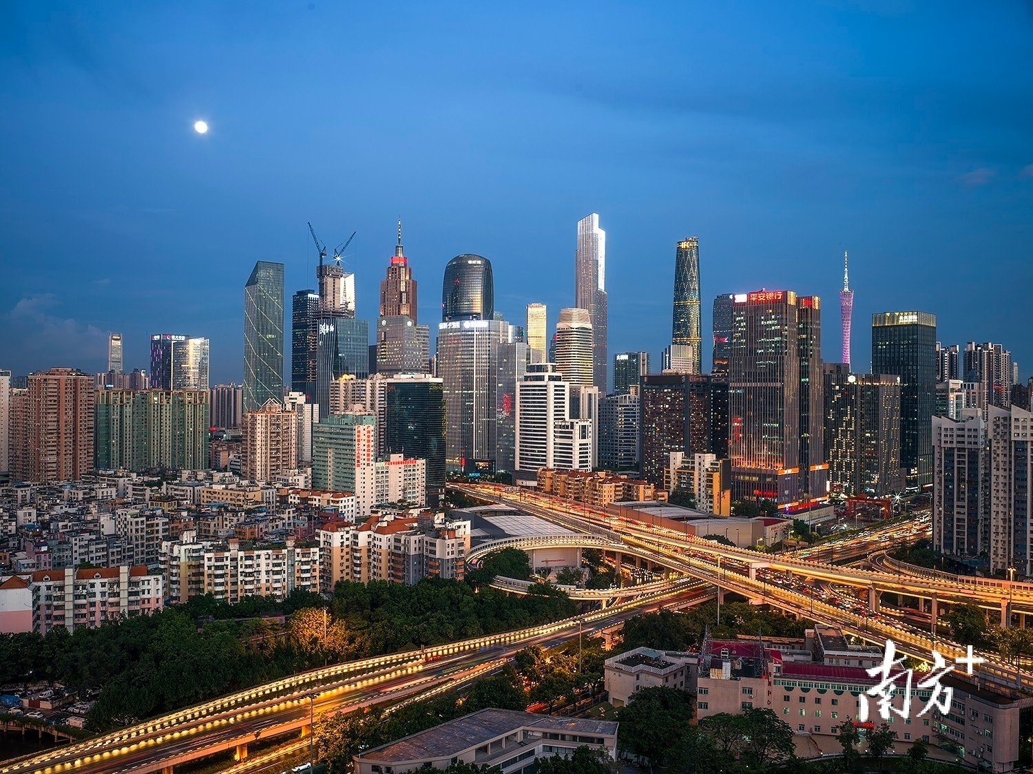 5月25日傍晚，日落后的霞光反射在广州珠江新城摩天大楼上，一轮明月缓缓升起。  逸松 摄