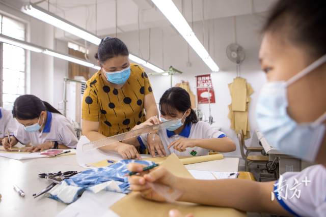 服装基础课上，科任教师手把手帮助聋生画草图。