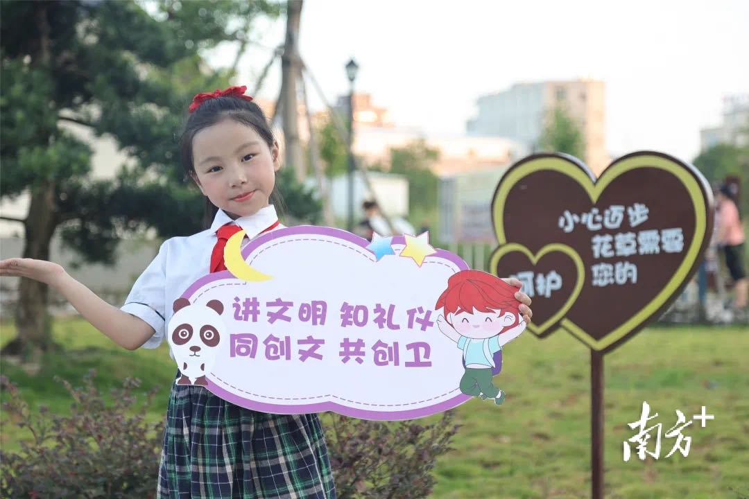 瓷都实验小学的 小学生们举起创卫创文宣传标语,争当"创卫创文小小
