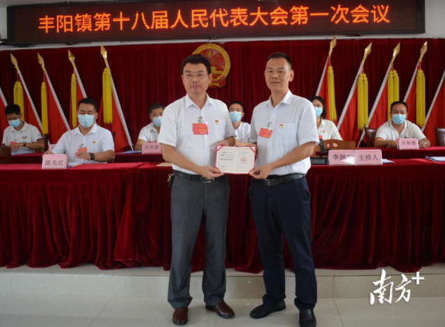 丰阳镇党委书记李剑平向镇人大主席邱伟峰（右）颁发当选证书。通讯员供图