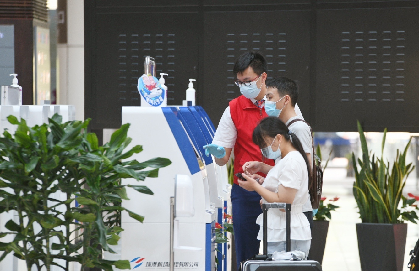 机场工作人员指引旅客办理自助值机。 