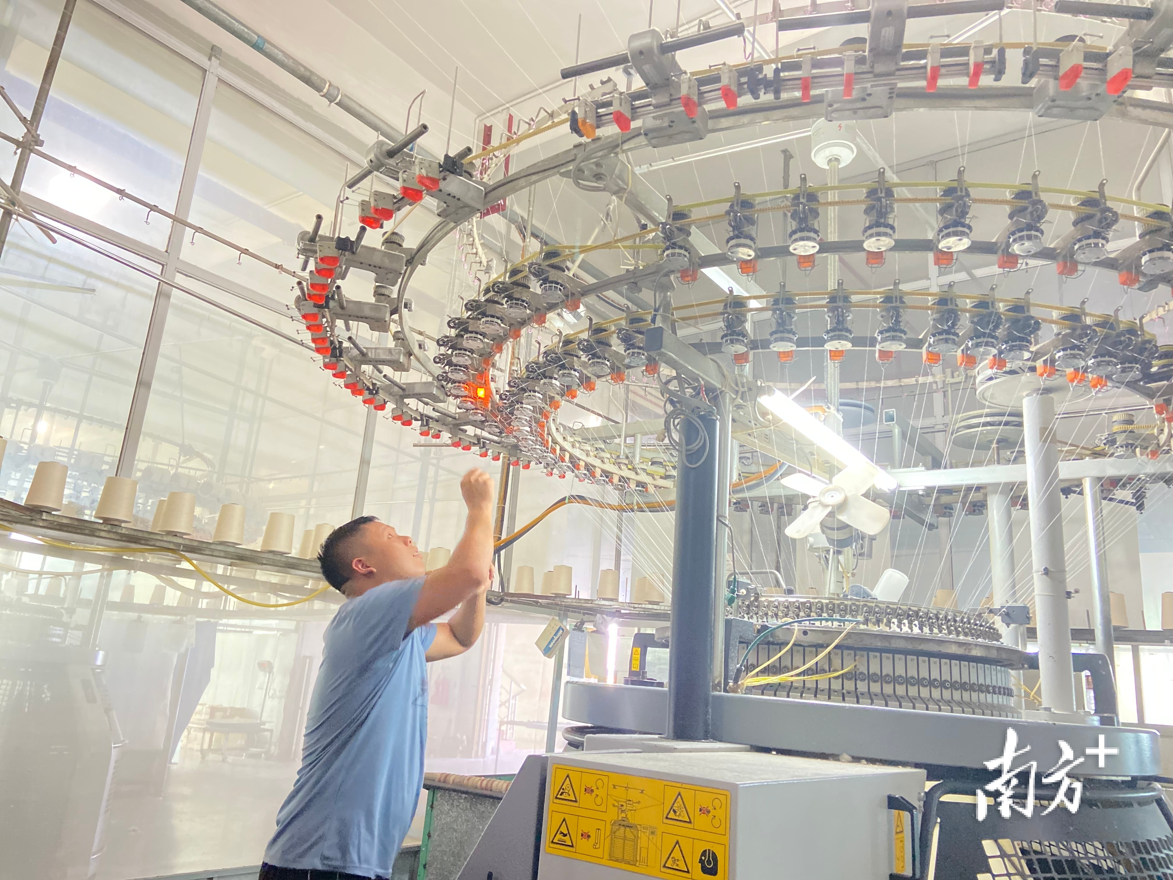 汇隆的生产车间里，工作人员在迈耶针织机旁“驳线”。陈梦 摄