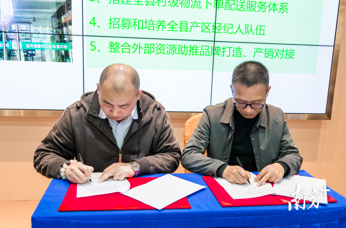  益农信息社（仁化）运营中心负责人宋德坤与中国邮政集团有限公司仁化县分公司副总经理江志敏进行仁化邮政与“村品通”平台签约仪式