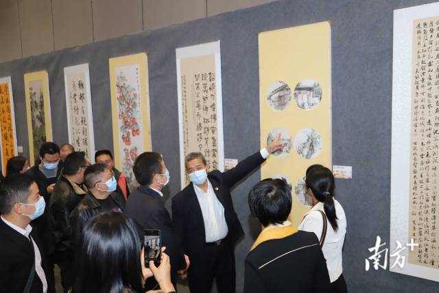 从化区文联主席唐石森向嘉宾介绍书画作品。