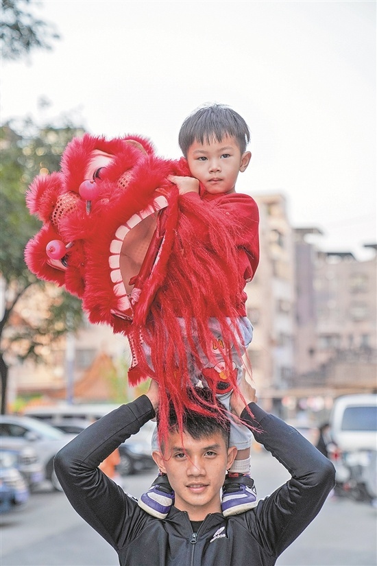 员村，罗定国和他的儿子罗晟玮。不到三岁的罗晟玮从小耳濡目染，如今舞起小狮头有模有样。
