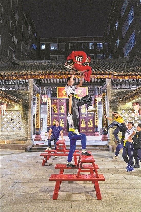 14岁的王智铭高高举起队友。他们正在车陂村内的晴川苏公祠练习凳狮的基本步伐。