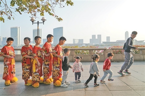 临江大道旁，广州市泰晟龙狮团团长罗定国带着舞狮少年们在江边一起跑步。
