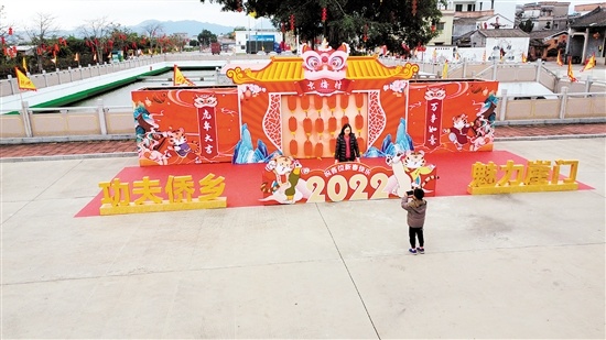 京梅村村民在背景墙前拍照，为自己增添年味。