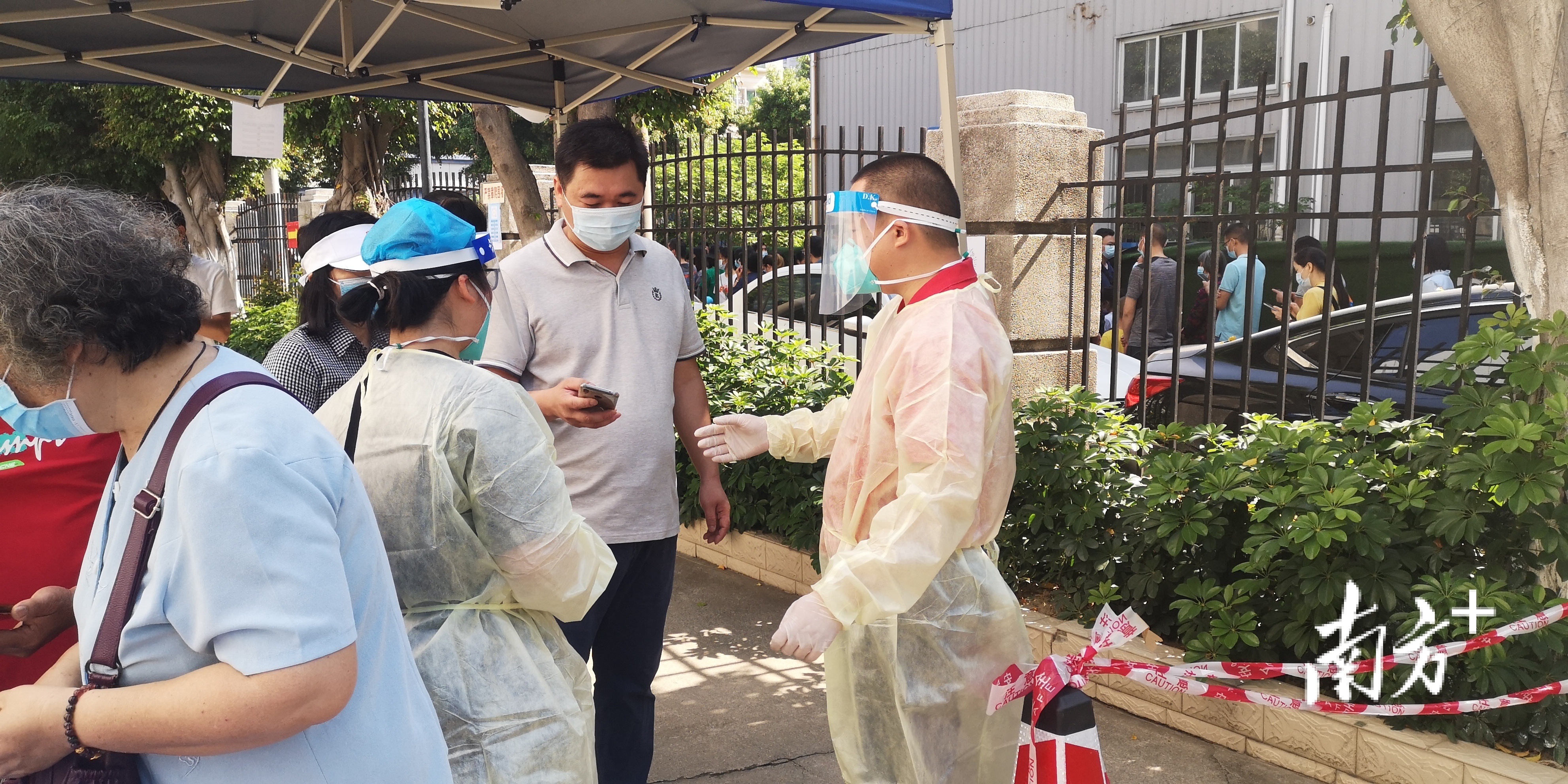 王福利(右)与同事参与冼可澄纪念小学核酸检测点志愿服务。卢浩能摄 王福利(右)与同事参与冼可澄纪念小学核酸检测点志愿服务。卢浩能摄