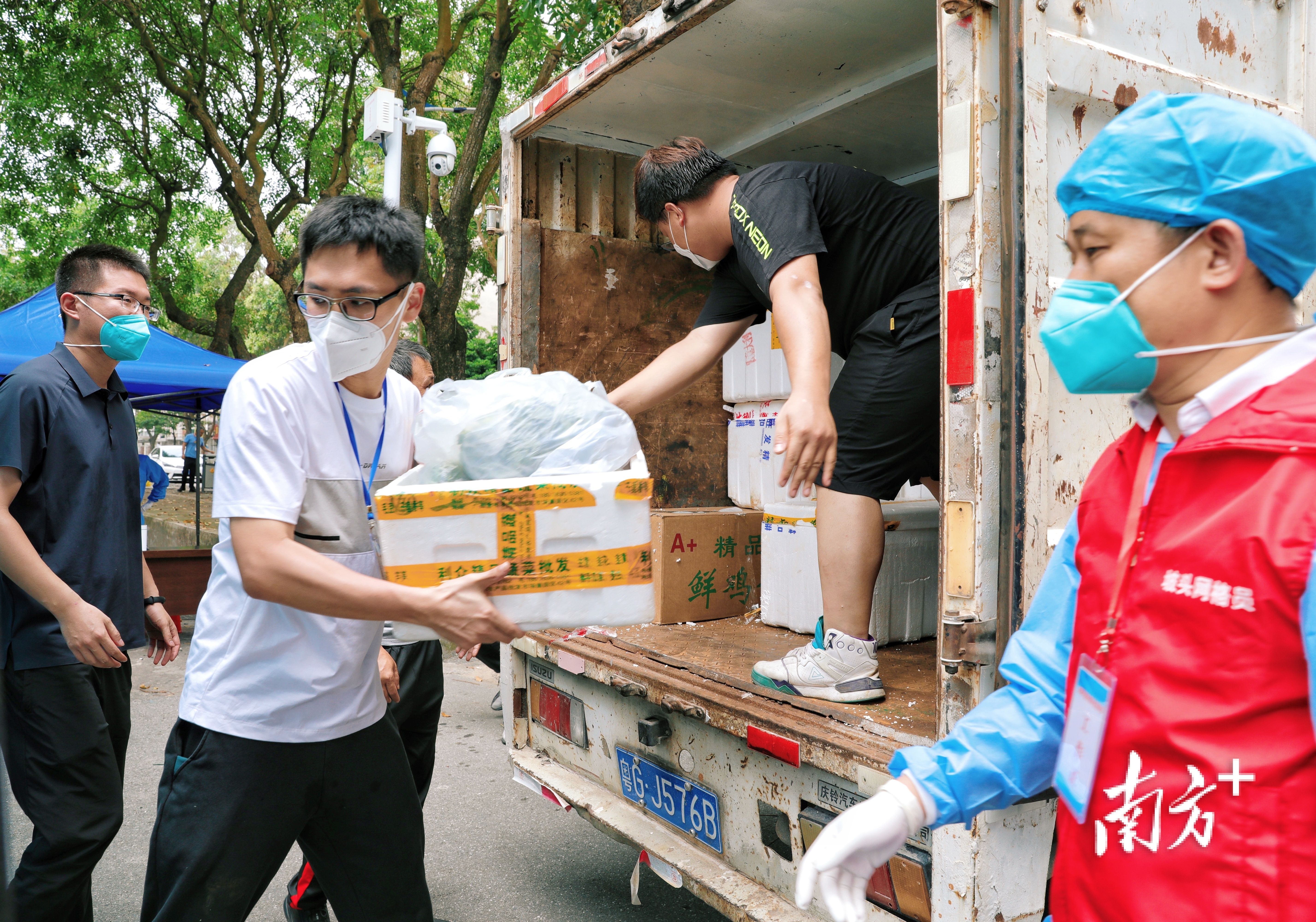 坡头区南调街道南油三区文明居南区门口，工作人员在装卸物资，准备配送。