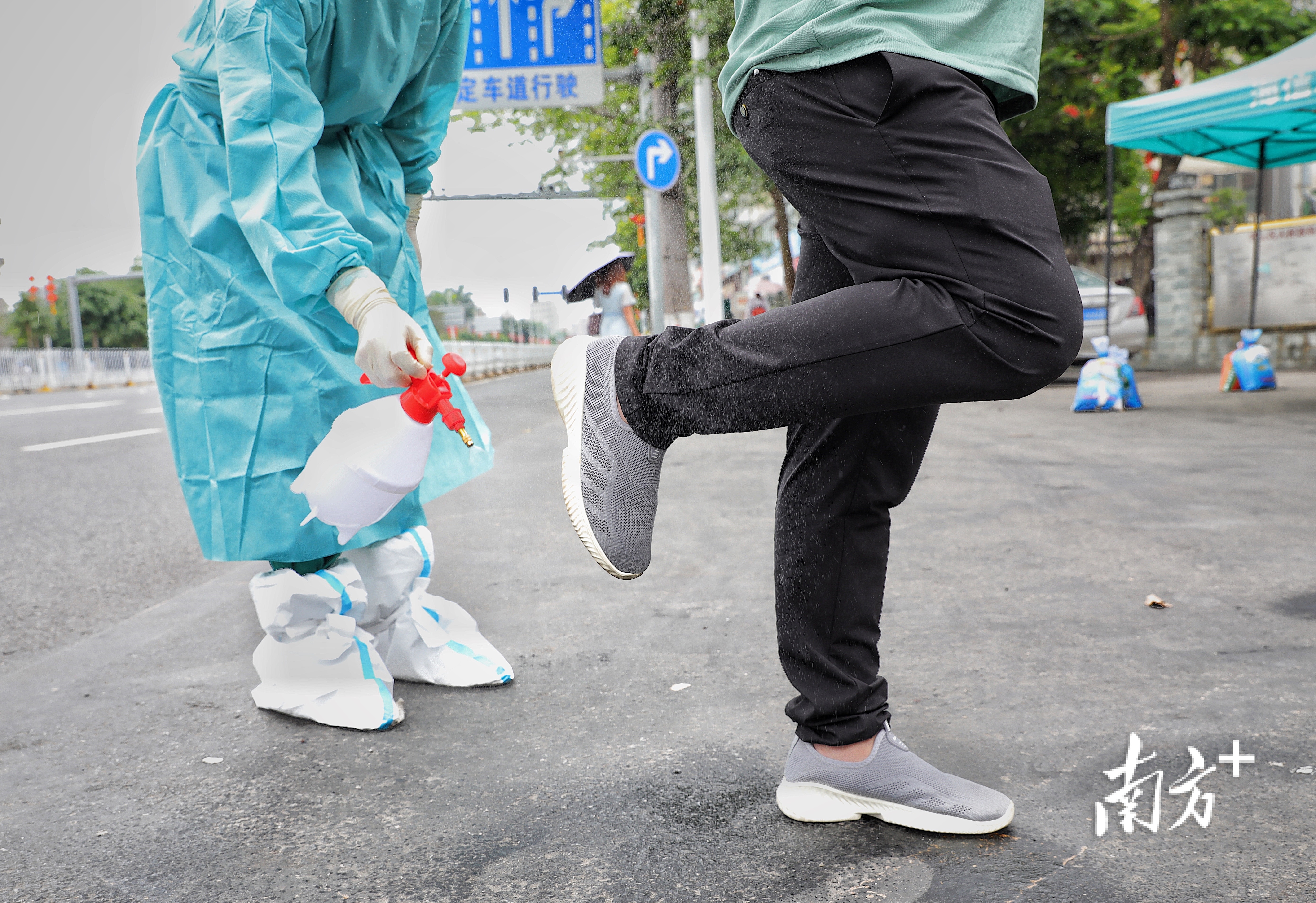 坡头区海东市场附近，防疫人员对人们进行全身的酒精消毒。