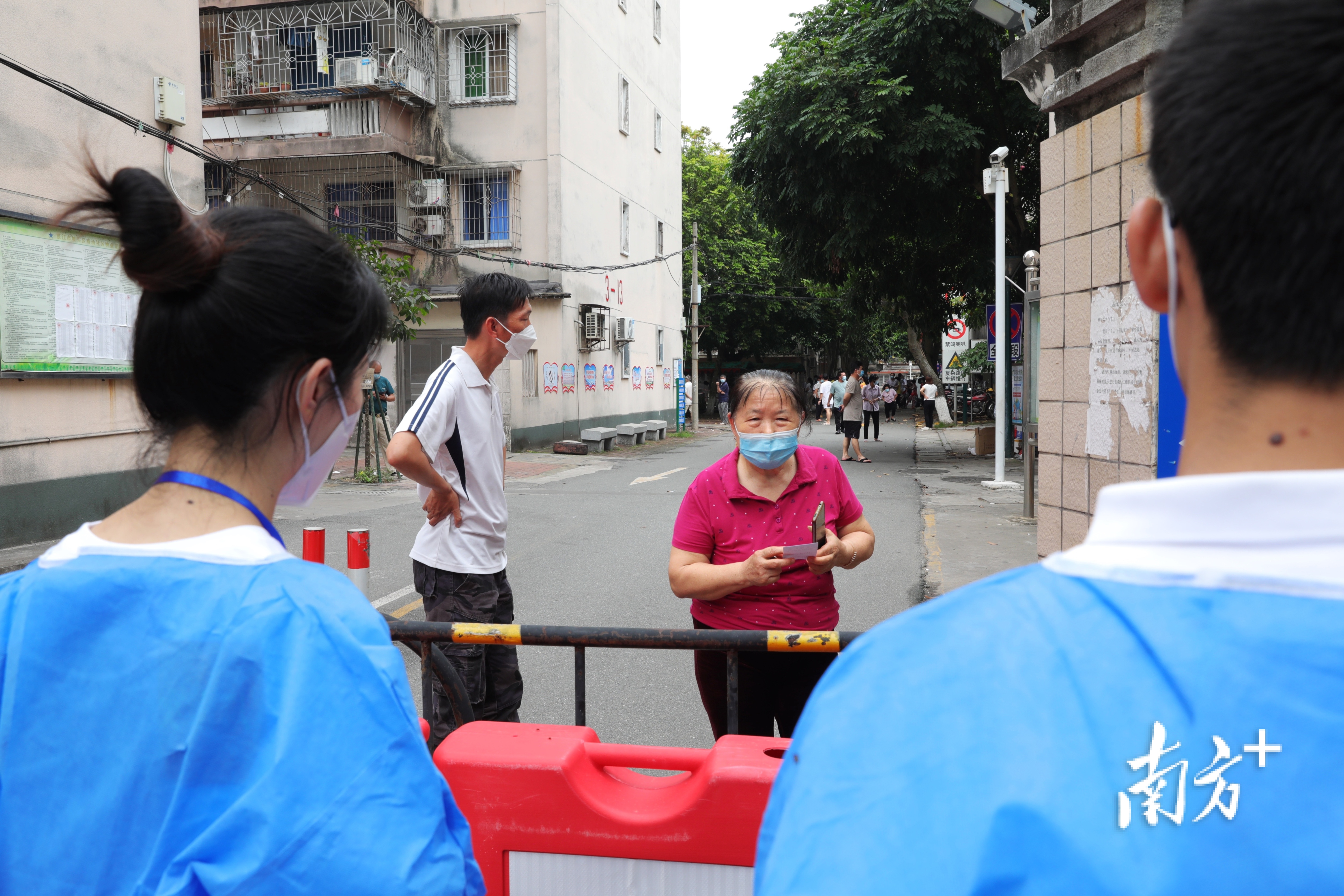坡头区南调街道南油三区文明居北区管控点，居民在向防疫人员咨询防疫政策。