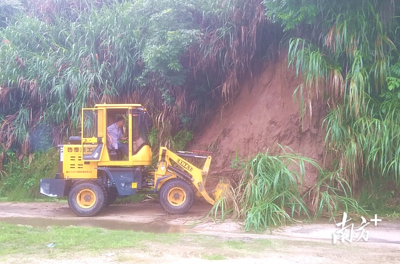 人大代表黄志标驾驶自家的小型挖掘机清理塌方路段。