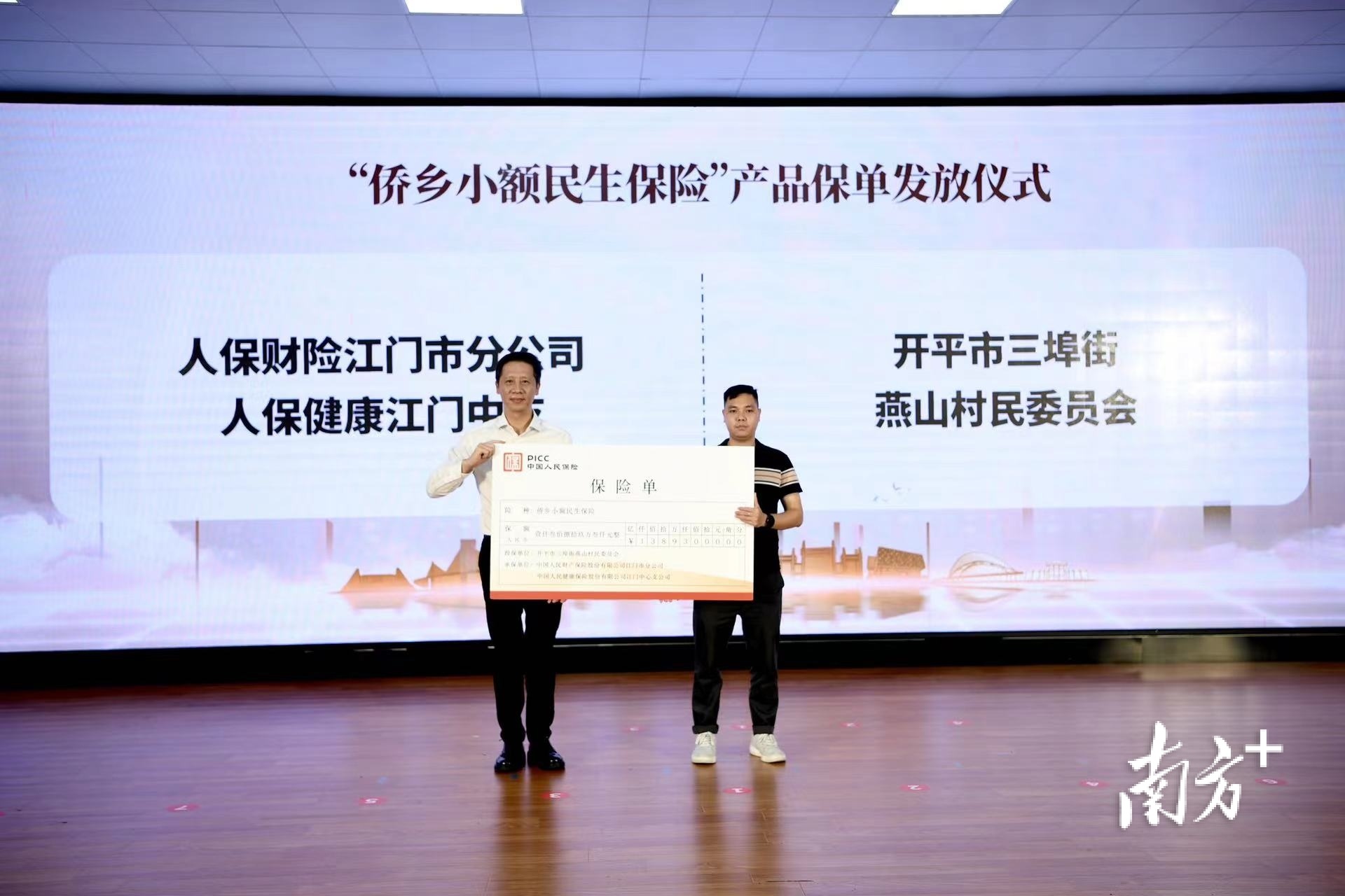推进会上，人保财险江门市分公司陈焯燕总经理为开平市三埠街燕山村民委员会发放“侨乡小额民生保险”保单。  南方+ 杨兴乐 拍摄