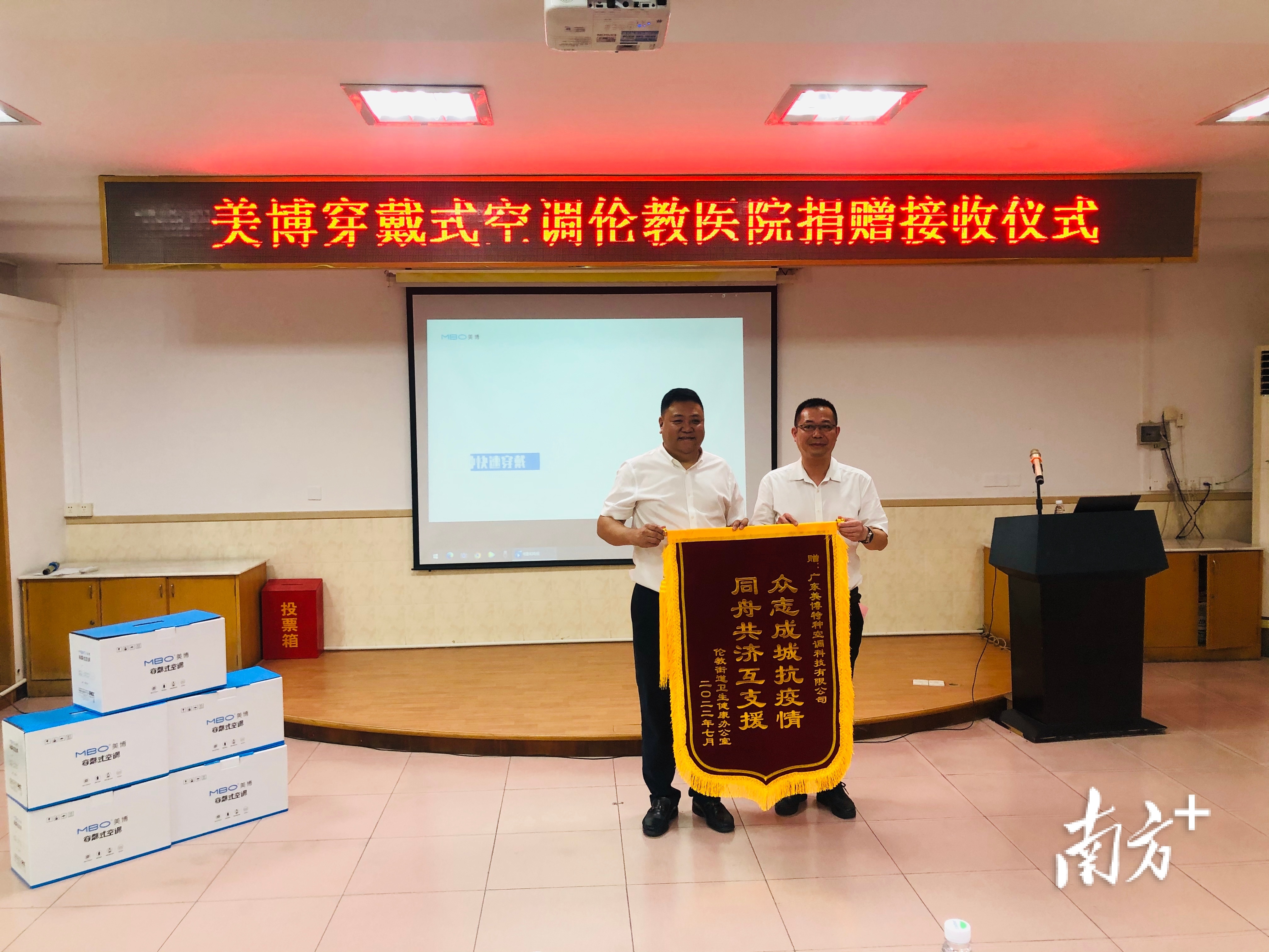 伦教街道党工委书记叶善楷（右）向美博空调董事长余方文赠送锦旗。 欧阳少伟 摄