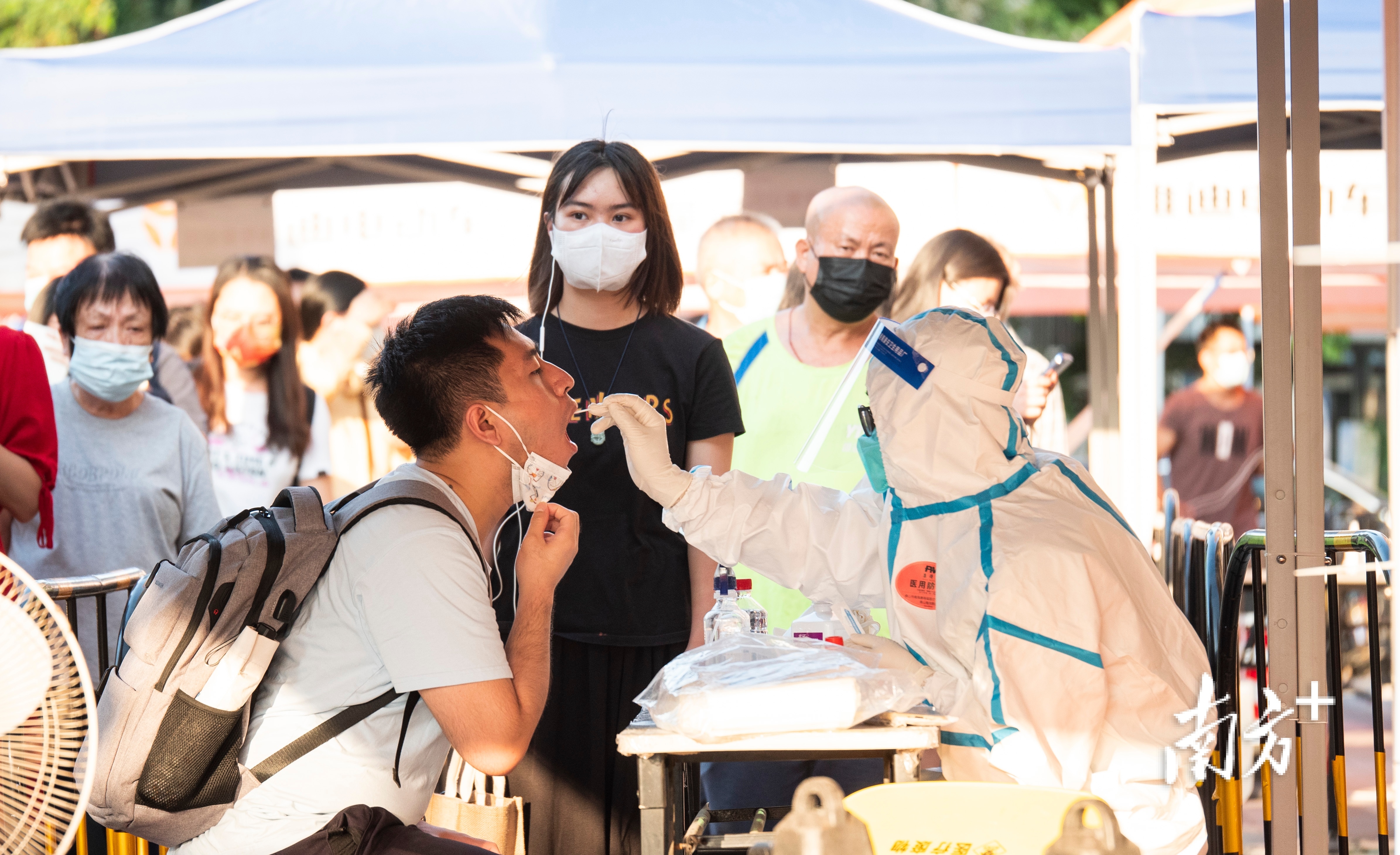 烈日下，穿着防护服的医护人员正在为市民做核酸。 姚佳烁 拍摄