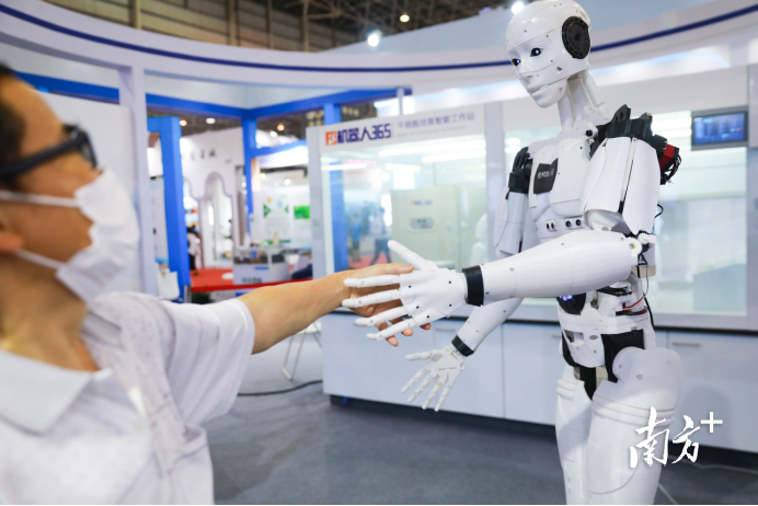 防疫用品生物科技馆，观众跟展出的实验室机器人握手。