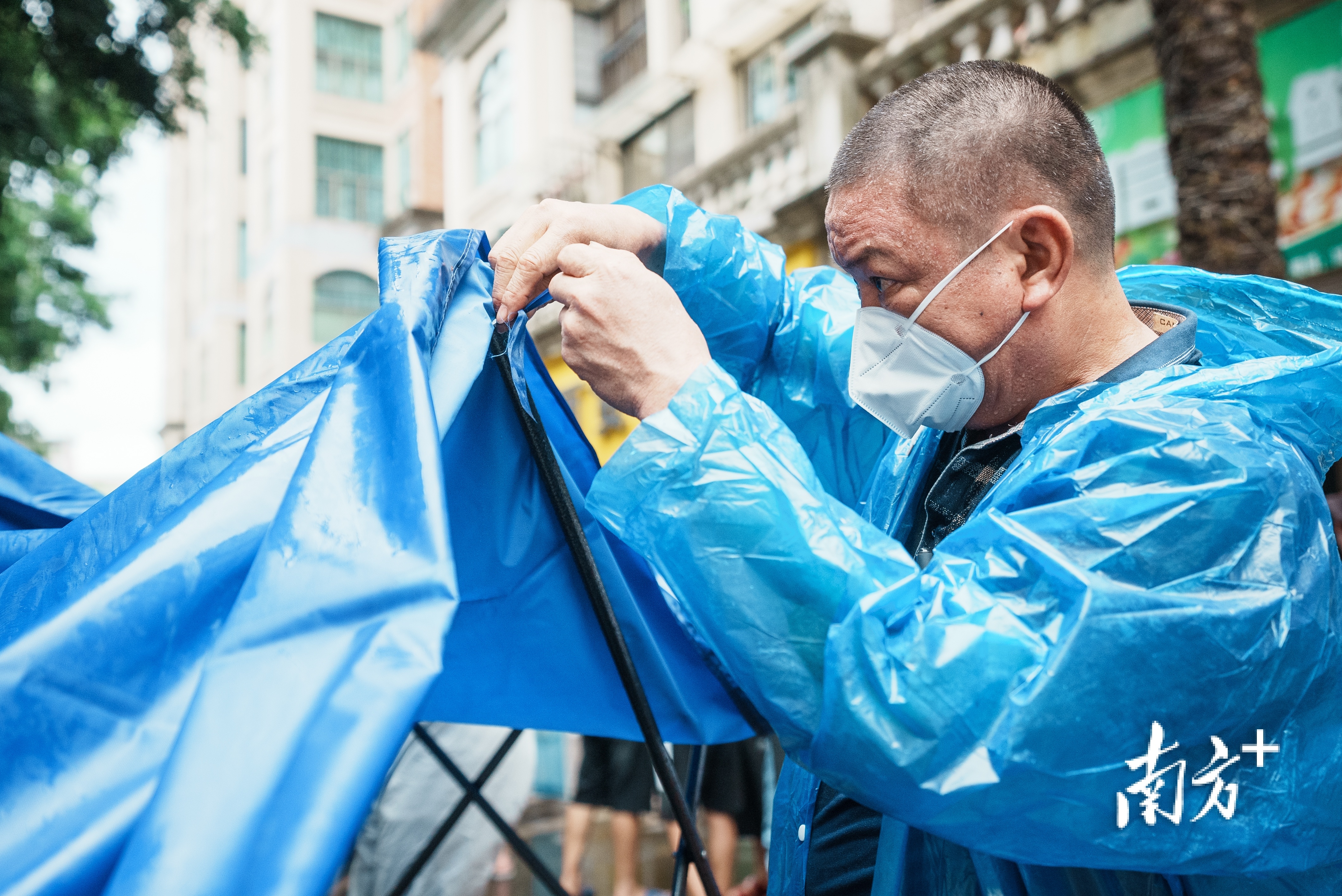 下雨天的核酸检测点,工作人员在安装遮雨设备