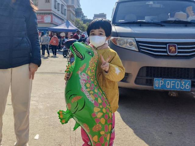 麻陂圩镇，正在试穿新鞋的小男孩，和如愿抱回气球的小女孩