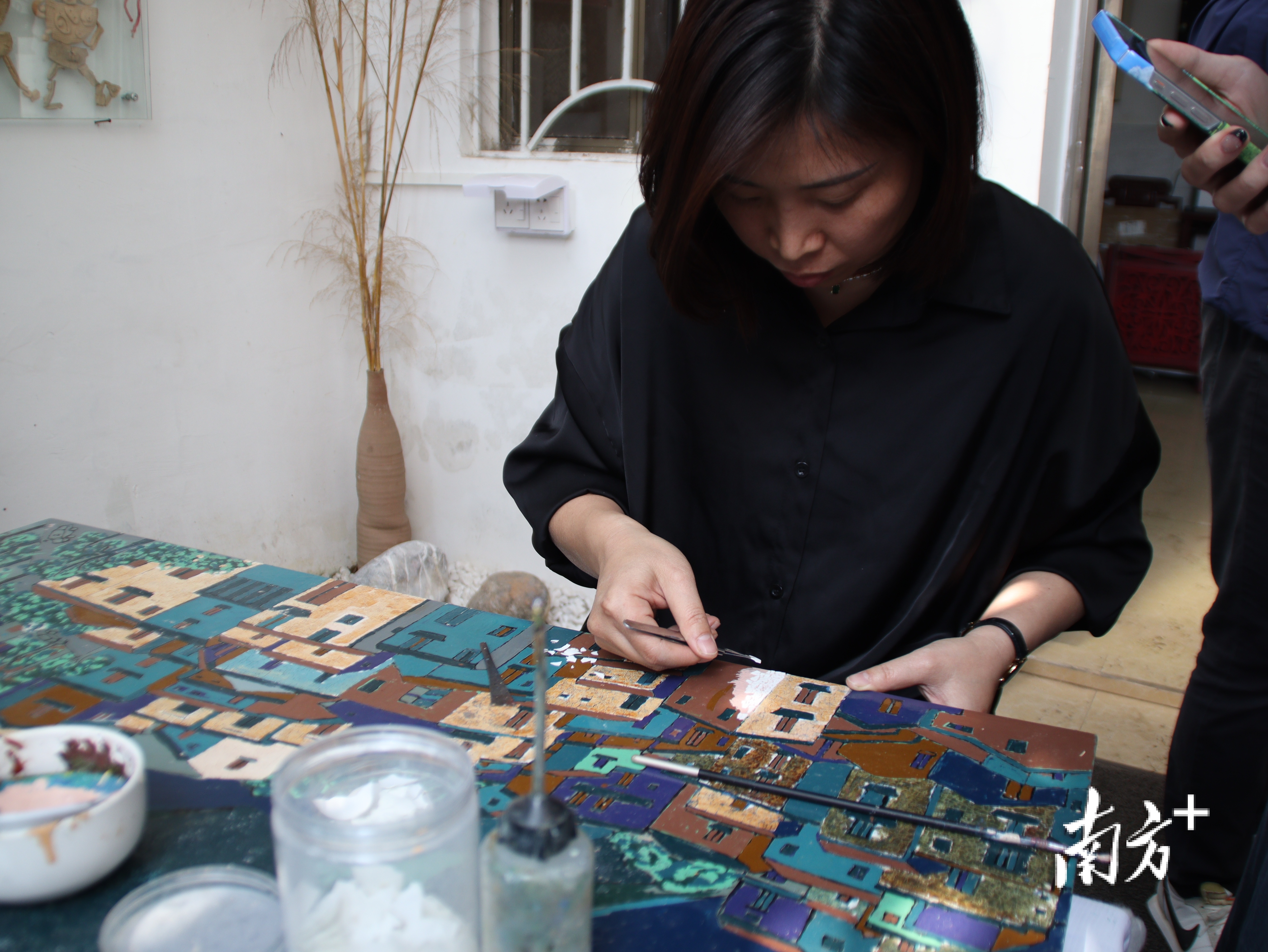 南风艺术部落成员陈敏枝正在为自己的漆画作品贴蛋壳。