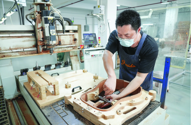 惠阳吉他产业逐渐撕掉代工标签，转向更具高附加值的品牌端。这是制琴匠人在给吉他琴箱定型。
