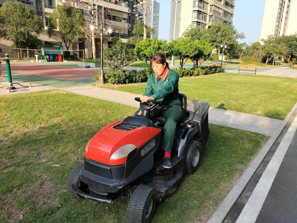 滕凤正熟练的操作推草机开展绿化工作。