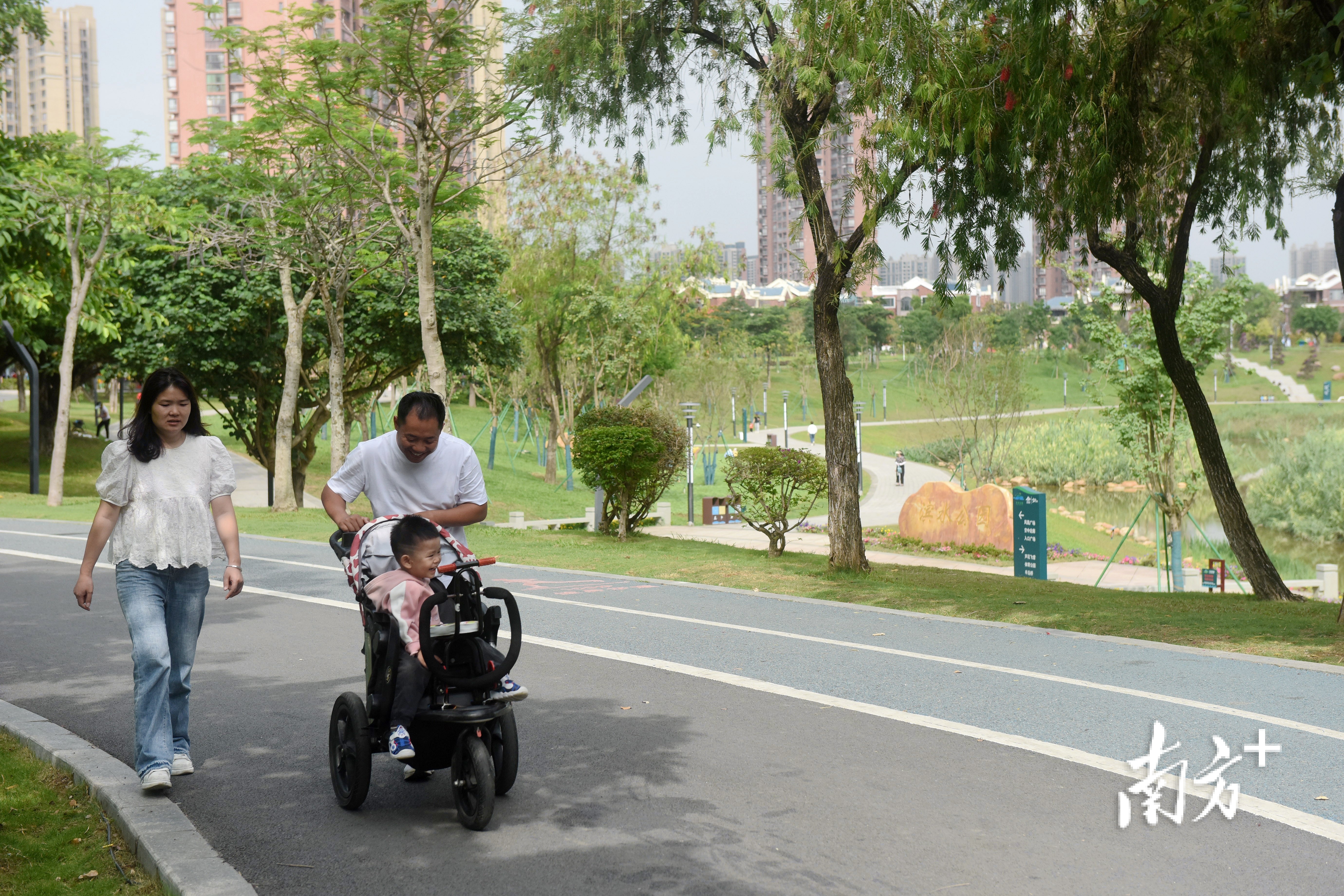 绿美的滨水公园里，市民在散步。 