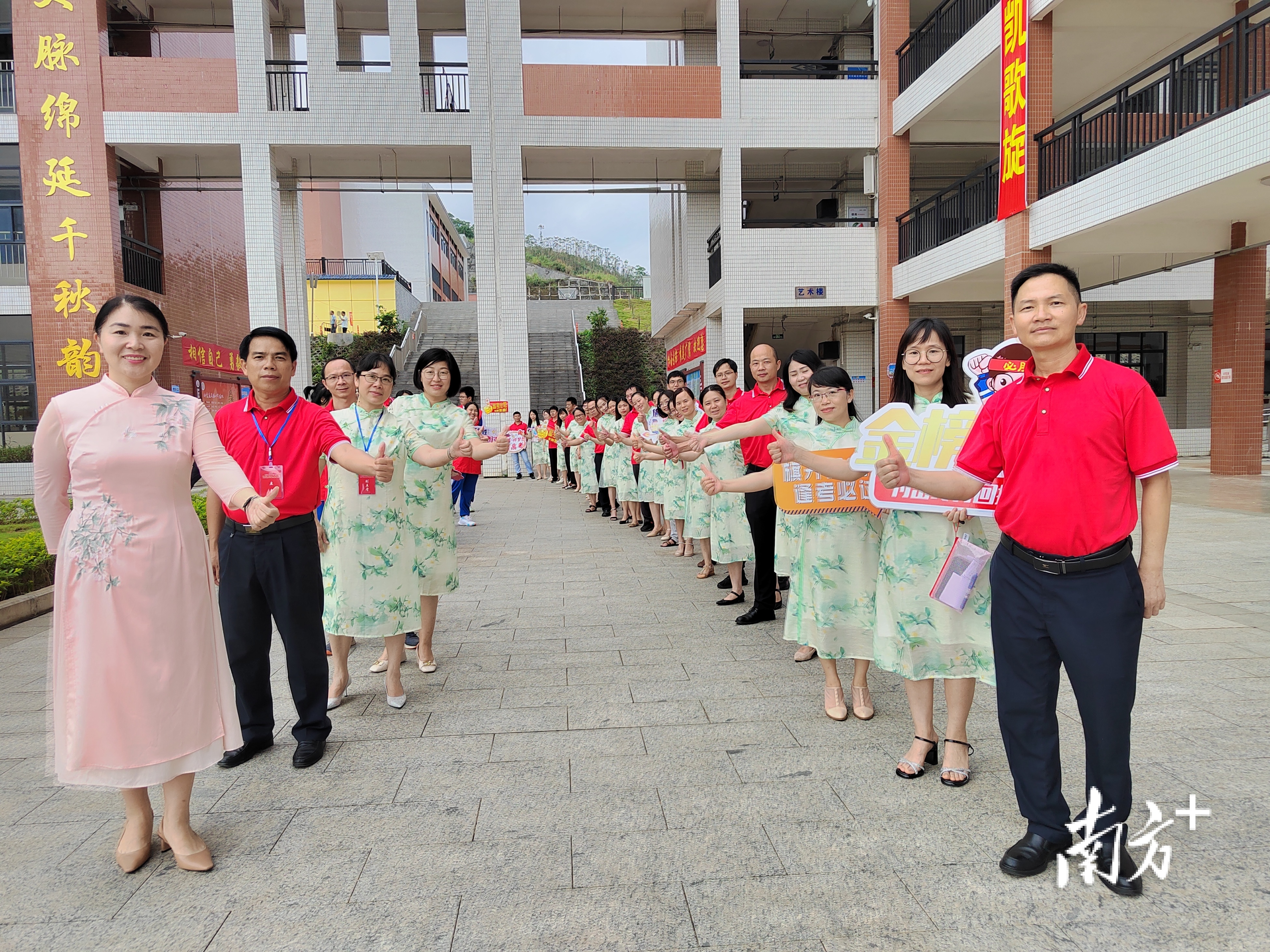 在封开县广信中学考点，穿着红绿相间衣服的老师排成列，给考生加油，寓意红红火火，一路绿灯。封开县融媒体中心 柴嘉蔚 摄