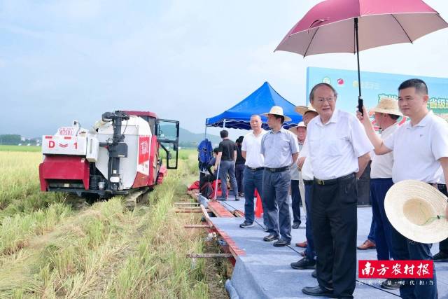罗锡文（右二）在现场察看农机设备。