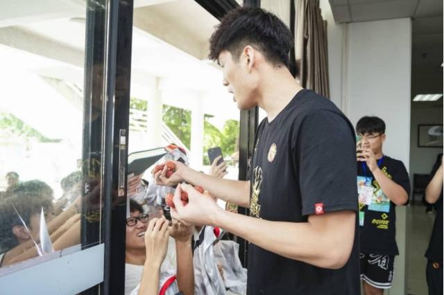 球迷们兴奋地接过陈国豪手中的荔枝。